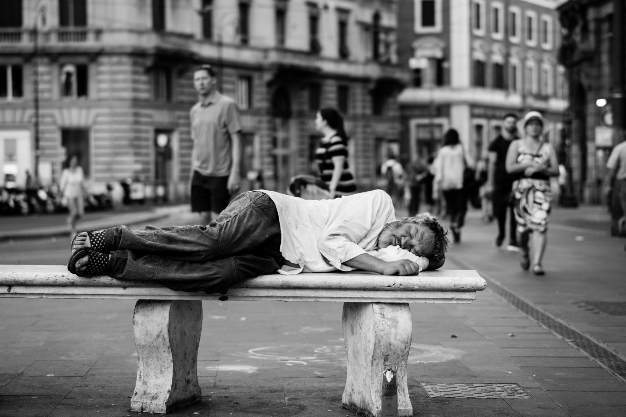 Homme défavorisé dormant sur un banc